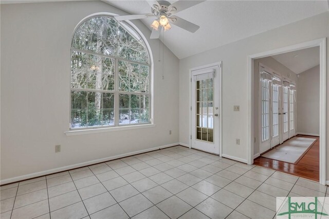 unfurnished dining area featuring french doors, ceiling fan, vaulted ceiling, and light tile patterned floors