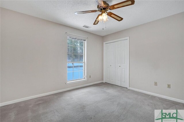 unfurnished bedroom with a textured ceiling, a closet, ceiling fan, and carpet