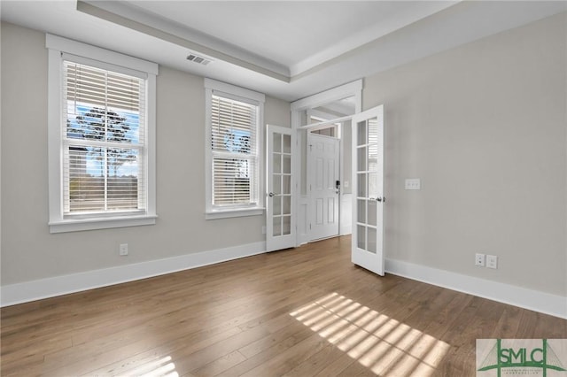 unfurnished room with french doors, a tray ceiling, and hardwood / wood-style flooring