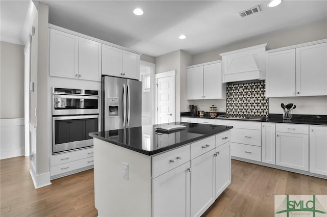 kitchen featuring stainless steel appliances, a center island, white cabinets, custom exhaust hood, and light wood-type flooring