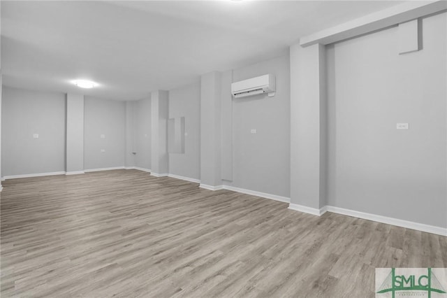 basement with a wall unit AC and light wood-type flooring