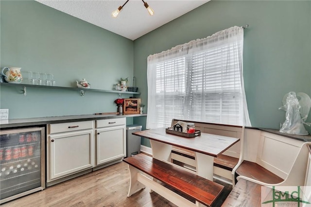 kitchen featuring white cabinetry, beverage cooler, and light hardwood / wood-style flooring