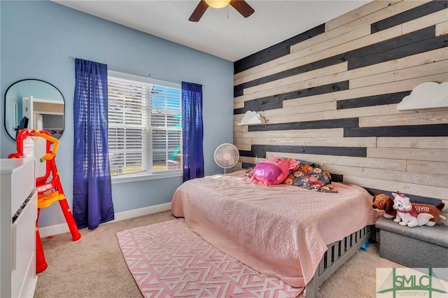 carpeted bedroom featuring wooden walls and ceiling fan