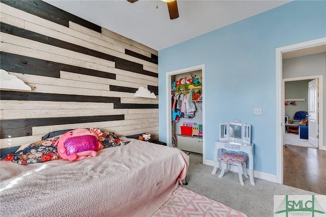 bedroom with wooden walls, ceiling fan, and carpet flooring