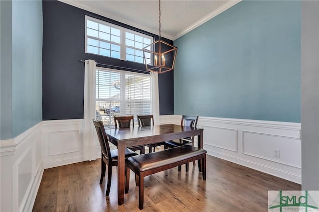 dining room with crown molding, hardwood / wood-style flooring, a textured ceiling, and a notable chandelier