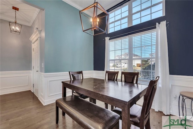 dining space with crown molding, wood-type flooring, and a notable chandelier