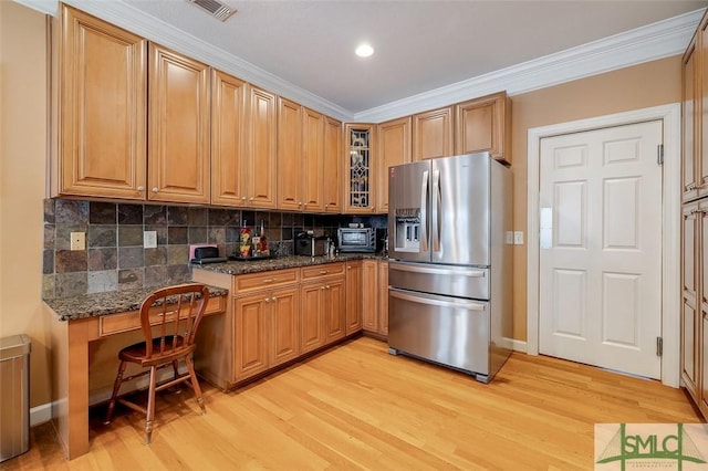 kitchen featuring stainless steel refrigerator with ice dispenser, ornamental molding, dark stone counters, light hardwood / wood-style floors, and backsplash