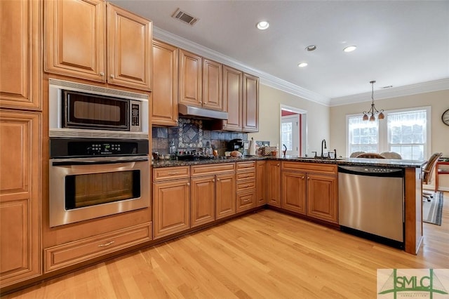 kitchen featuring sink, backsplash, hanging light fixtures, kitchen peninsula, and stainless steel appliances