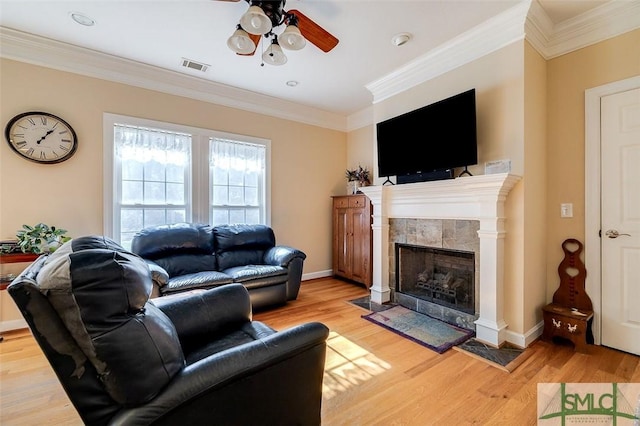 living room with crown molding, ceiling fan, a fireplace, and light hardwood / wood-style floors