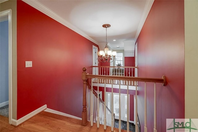 staircase with an inviting chandelier, hardwood / wood-style flooring, and ornamental molding