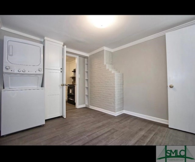 clothes washing area featuring dark wood-type flooring, ornamental molding, and stacked washer / drying machine