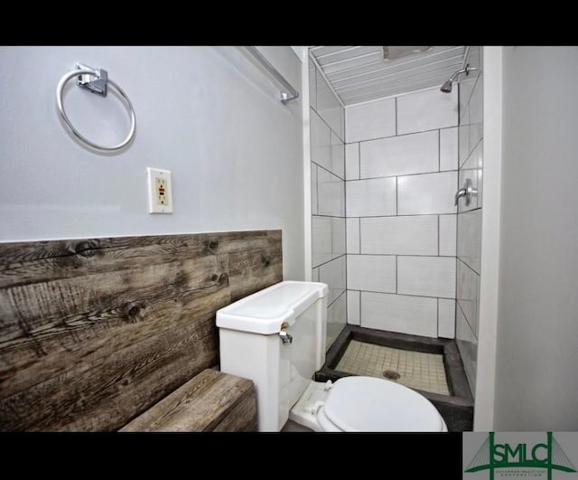 bathroom with a tile shower and toilet