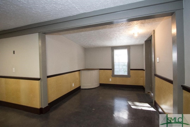 unfurnished room featuring a textured ceiling and wood walls