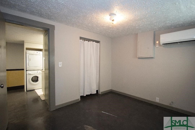 spare room featuring stacked washer / drying machine, a textured ceiling, and a wall mounted AC