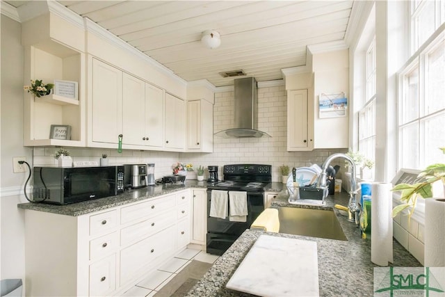 kitchen featuring tasteful backsplash, sink, light tile patterned floors, black appliances, and wall chimney range hood