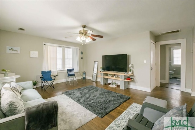 living room featuring dark wood-type flooring, ceiling fan, and plenty of natural light