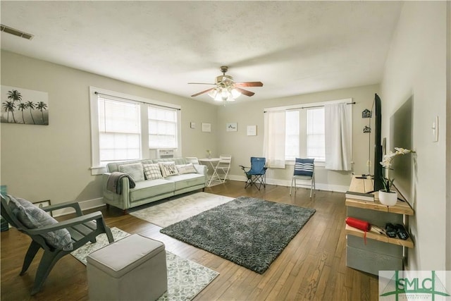 living room featuring dark hardwood / wood-style flooring, ceiling fan, and a healthy amount of sunlight