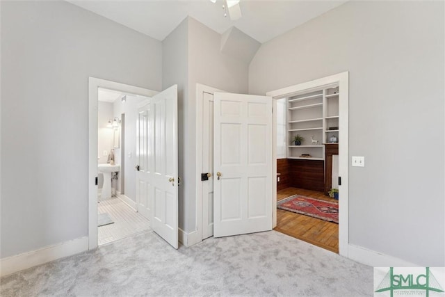 carpeted bedroom featuring lofted ceiling, ensuite bathroom, and a closet