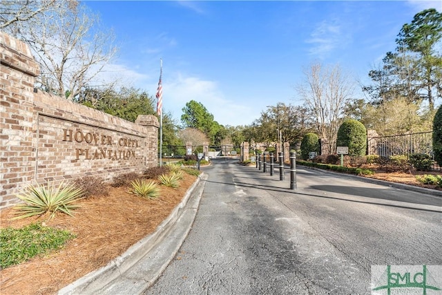 view of road featuring a gate, curbs, and a gated entry