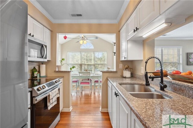 kitchen with white cabinetry, sink, light stone countertops, and appliances with stainless steel finishes