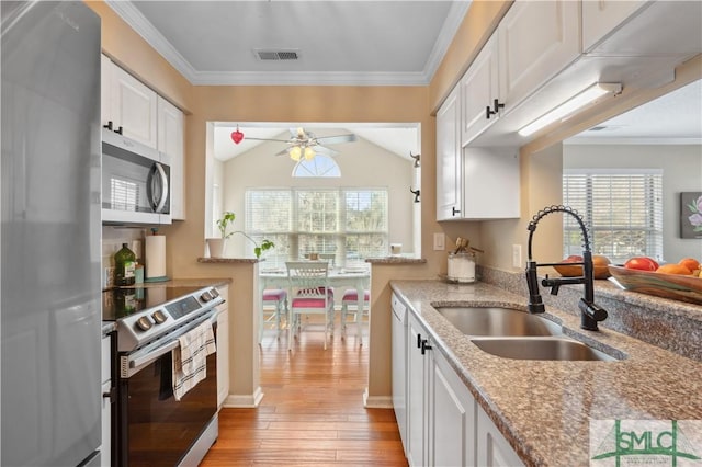 kitchen with stainless steel appliances, white cabinets, a sink, and light stone countertops