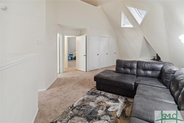 carpeted living room featuring a skylight and high vaulted ceiling