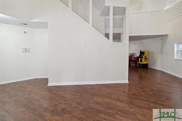 unfurnished living room featuring a high ceiling and dark hardwood / wood-style floors