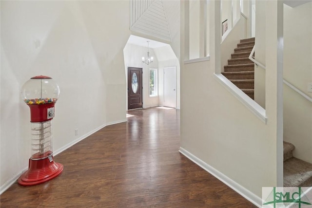 entryway with dark wood-type flooring, an inviting chandelier, and a towering ceiling