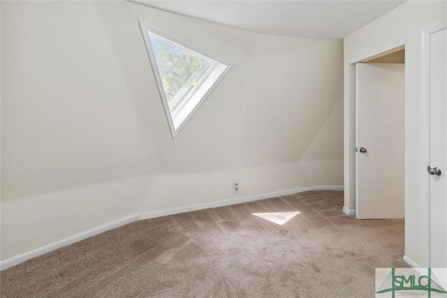 bonus room featuring vaulted ceiling with skylight and light carpet