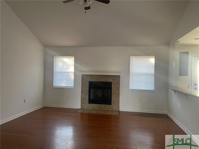 unfurnished living room featuring lofted ceiling, a healthy amount of sunlight, dark hardwood / wood-style floors, and a tile fireplace