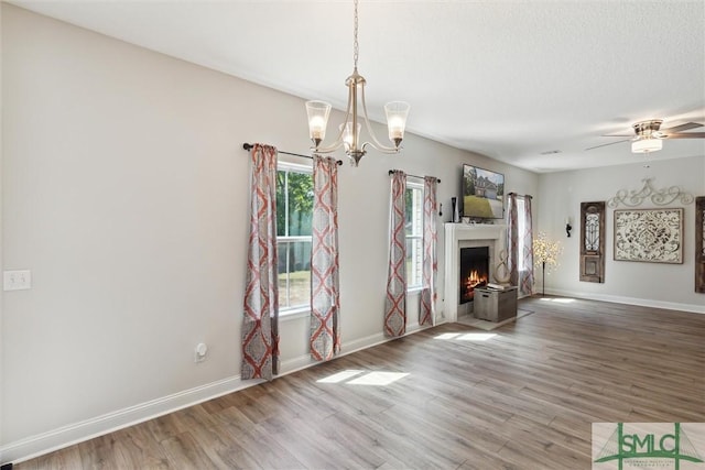 unfurnished living room with ceiling fan with notable chandelier, wood-type flooring, and a textured ceiling