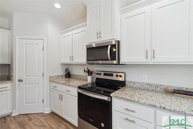 kitchen featuring stainless steel appliances, white cabinets, light stone counters, and light hardwood / wood-style flooring