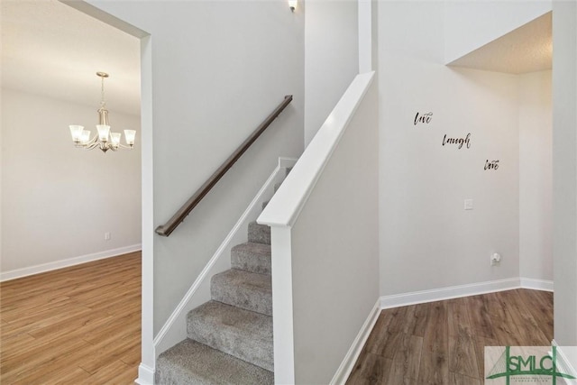 stairway featuring hardwood / wood-style floors and a notable chandelier