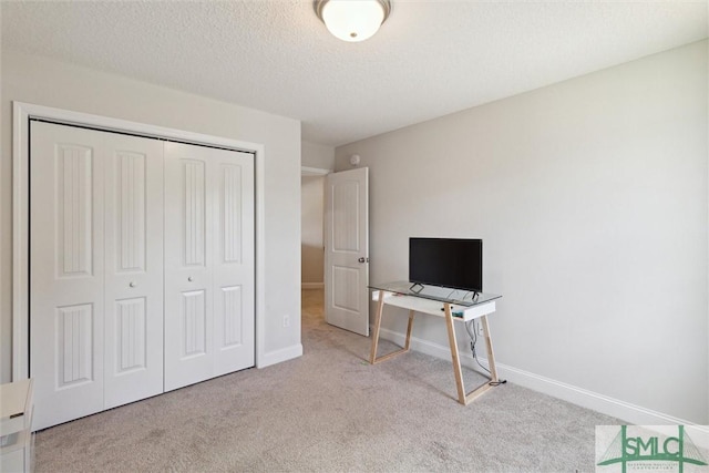 bedroom with light colored carpet, a textured ceiling, and a closet