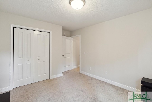 unfurnished bedroom featuring light colored carpet, a closet, and a textured ceiling