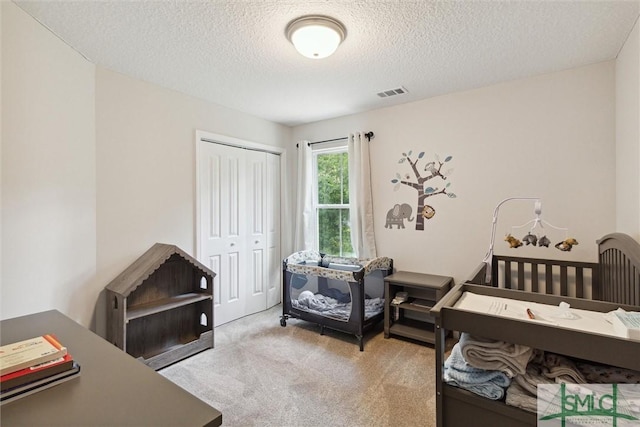 bedroom featuring light colored carpet, a closet, and a textured ceiling