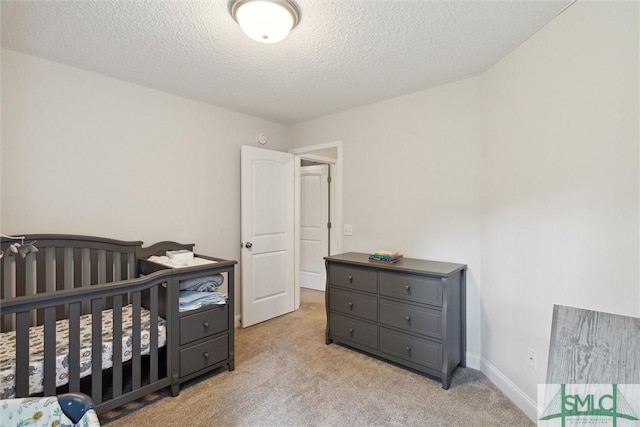 carpeted bedroom featuring a crib and a textured ceiling