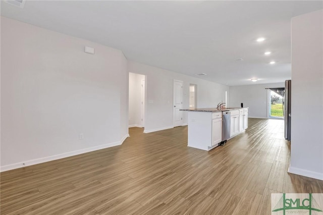 kitchen featuring sink, light hardwood / wood-style flooring, appliances with stainless steel finishes, a kitchen island with sink, and white cabinets