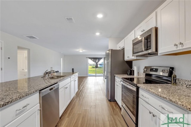 kitchen with white cabinetry, stainless steel appliances, sink, and light stone counters