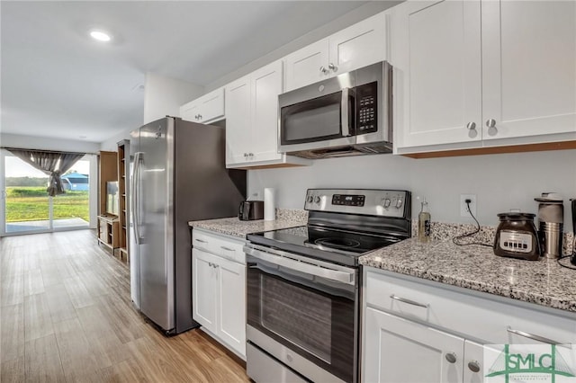 kitchen featuring white cabinetry, appliances with stainless steel finishes, light stone counters, and light hardwood / wood-style flooring