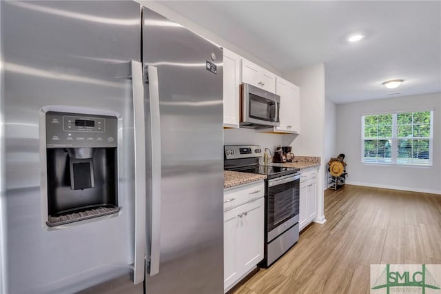 kitchen featuring white cabinetry, light stone counters, light hardwood / wood-style flooring, and stainless steel appliances