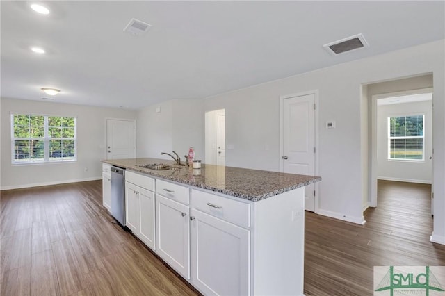 kitchen with sink, an island with sink, white cabinets, stone countertops, and stainless steel dishwasher