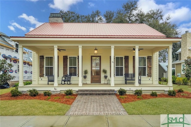 view of front of house with ceiling fan, covered porch, and a front lawn