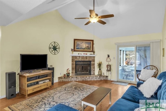 living room featuring ceiling fan, lofted ceiling, a fireplace, and light hardwood / wood-style flooring