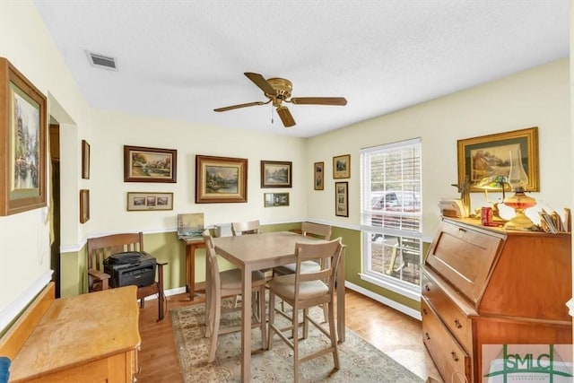 dining space with ceiling fan, light hardwood / wood-style floors, and a textured ceiling