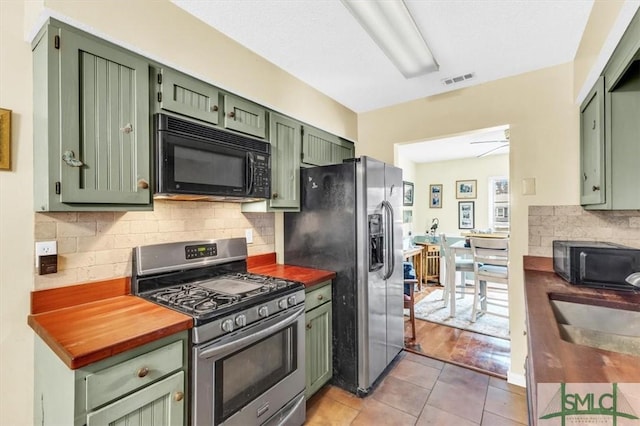 kitchen with appliances with stainless steel finishes, tasteful backsplash, sink, green cabinets, and light tile patterned floors