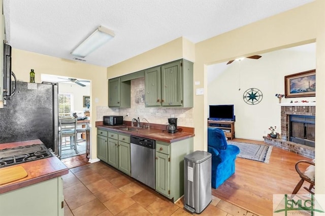 kitchen featuring sink, green cabinetry, light tile patterned floors, appliances with stainless steel finishes, and ceiling fan