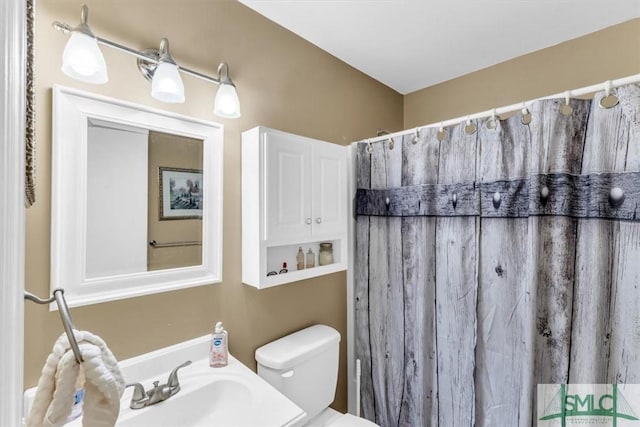 bathroom featuring sink, a shower with shower curtain, and toilet