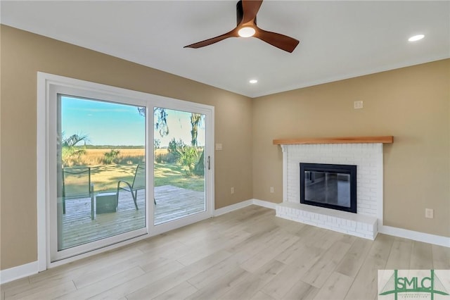 unfurnished living room with ceiling fan, a fireplace, and light wood-type flooring