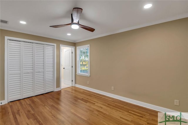 unfurnished bedroom with ceiling fan, ornamental molding, a closet, and light wood-type flooring